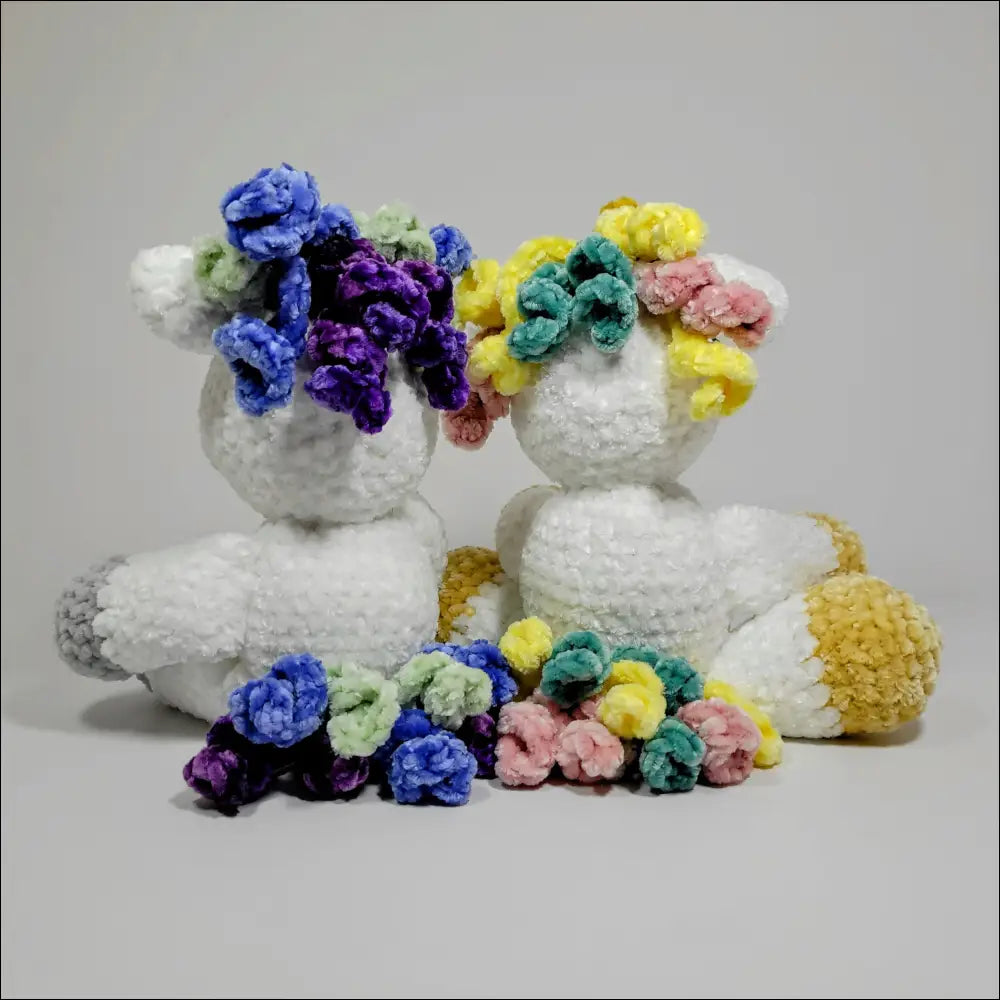 Two cute stuffed sheeps with flowers on their heads next to a Unicorn Plush for checkout