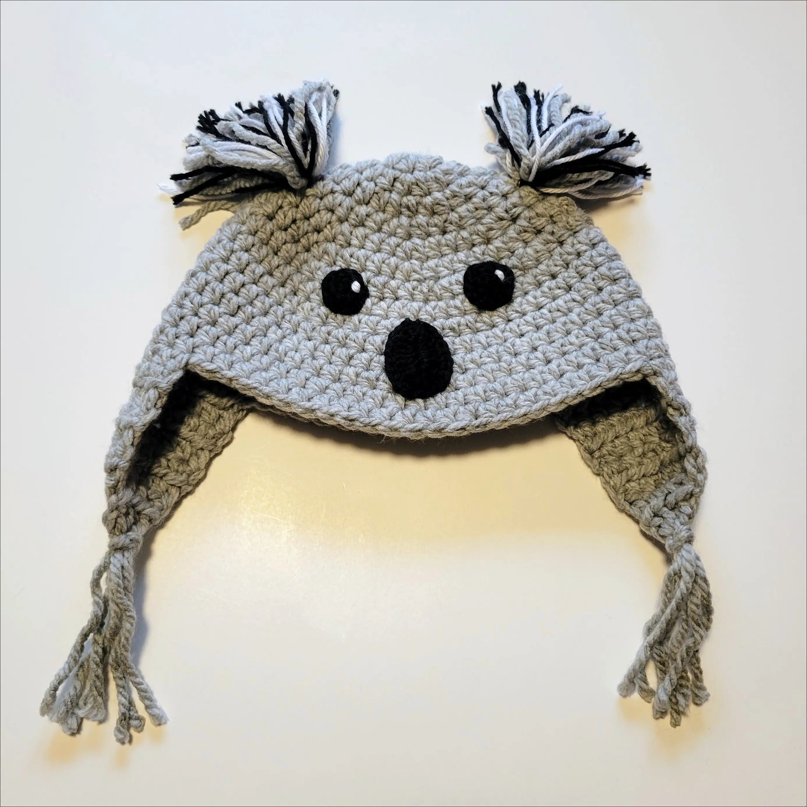 Crocheted gray koala hat with ear flaps and tassels for animal hat lovers