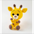 Crocheted baby giraffe plush toy in yellow with brown spots from a cute giraffe pattern baby