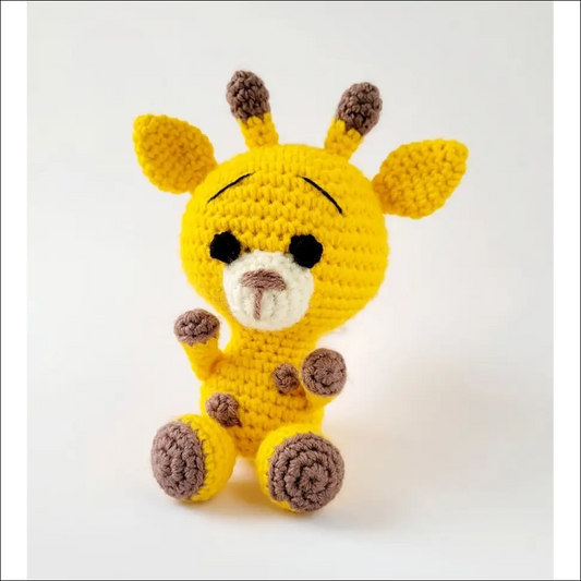 Crocheted baby giraffe plush toy in yellow with brown spots from a cute giraffe pattern baby