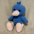 Blue crochet duck toy on a beige fabric background