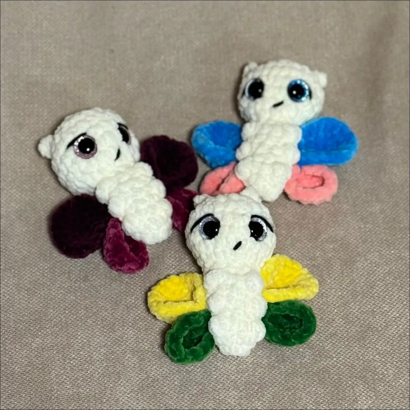 Three colorful butterfly-shaped hair ties on a beige background