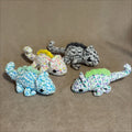 Four colorful chameleon toys on a brown surface