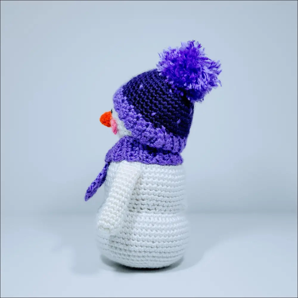 Cute crochet snowman with a purple hat, scarf, and a fun red nose