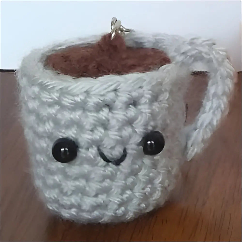 Crocheted white coffee cup with a cute face and brown drink inside for trendy vibes