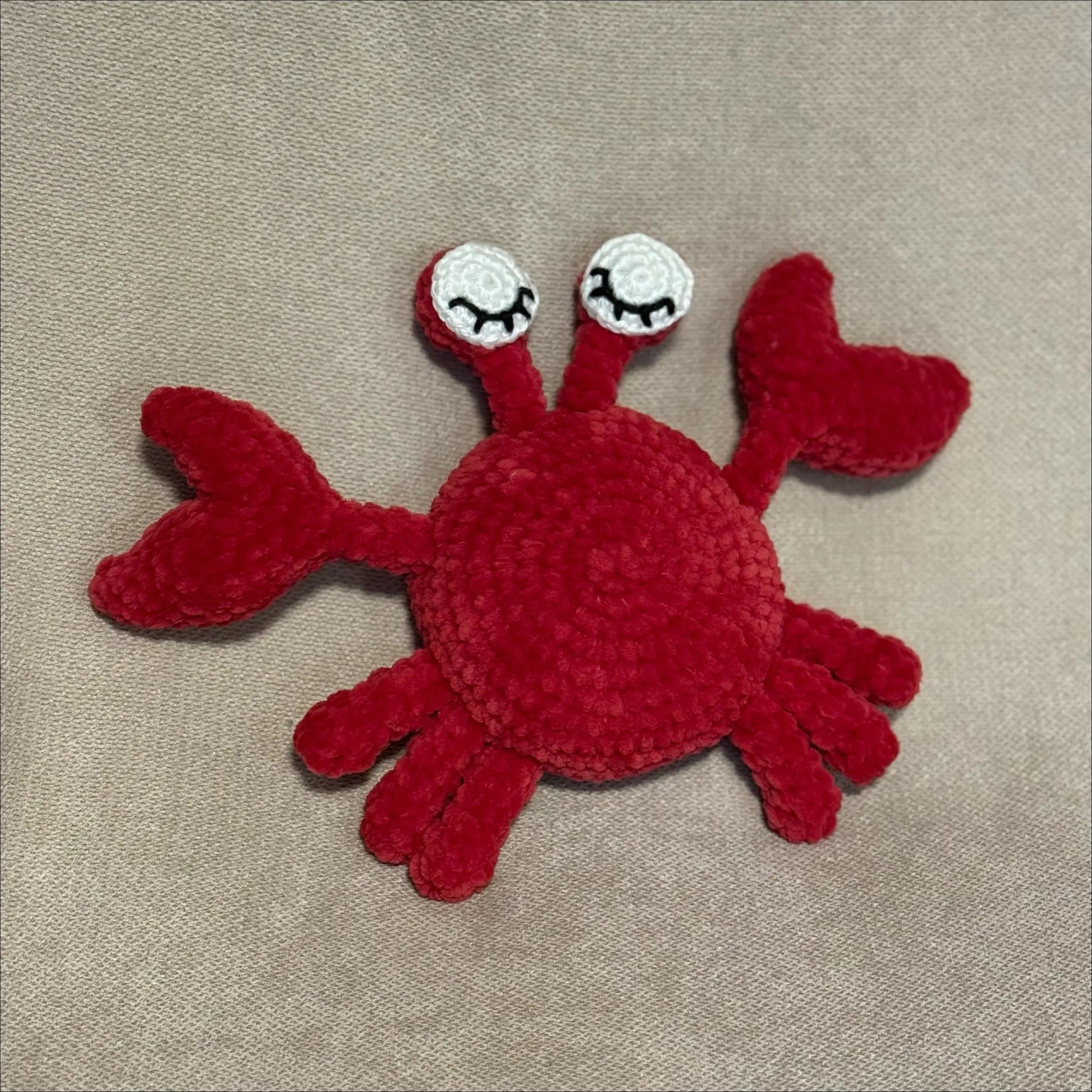 Red crab-shaped toy on a beige fabric background