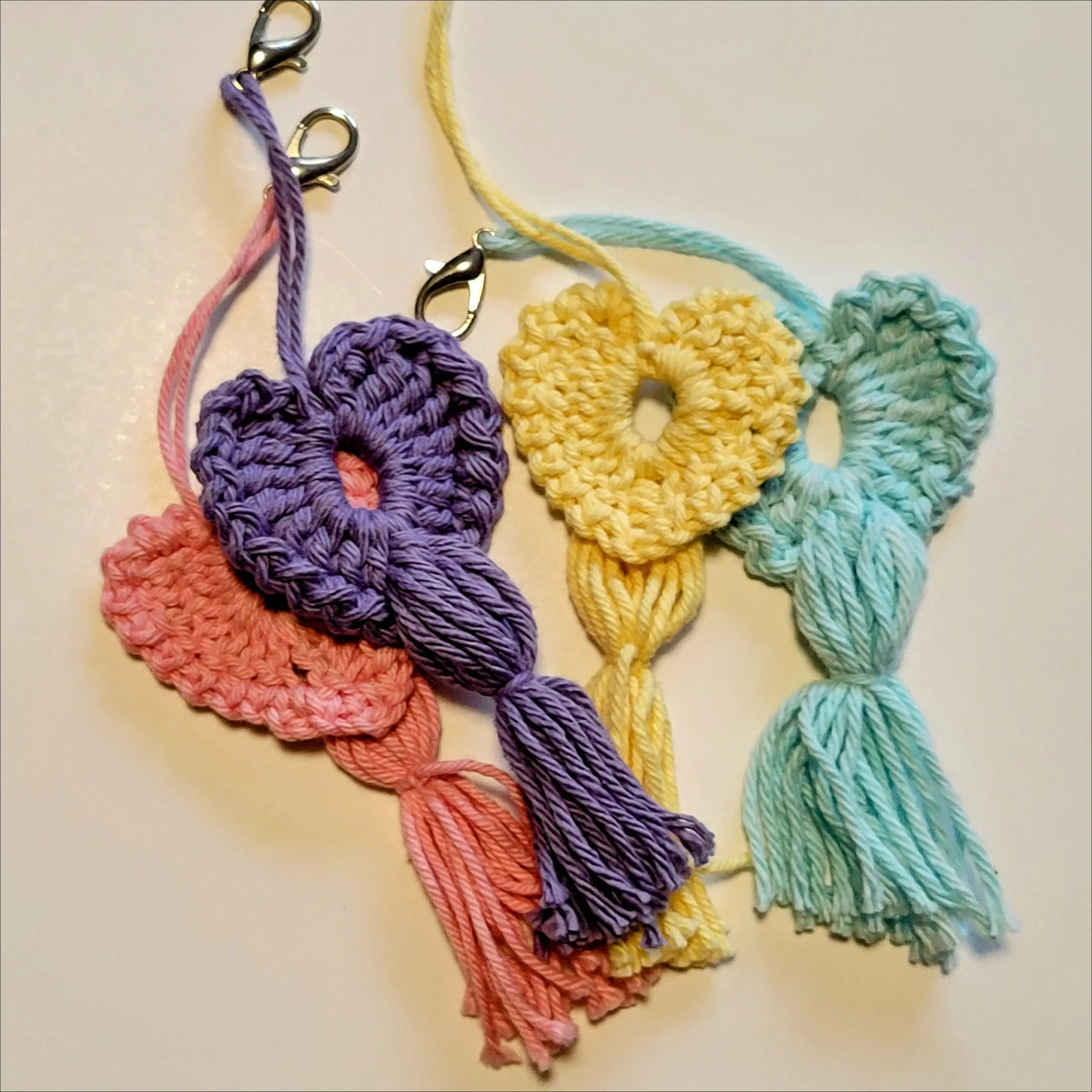 Colorful crocheted heart-shaped keychains with tassels for your coffee cup delight