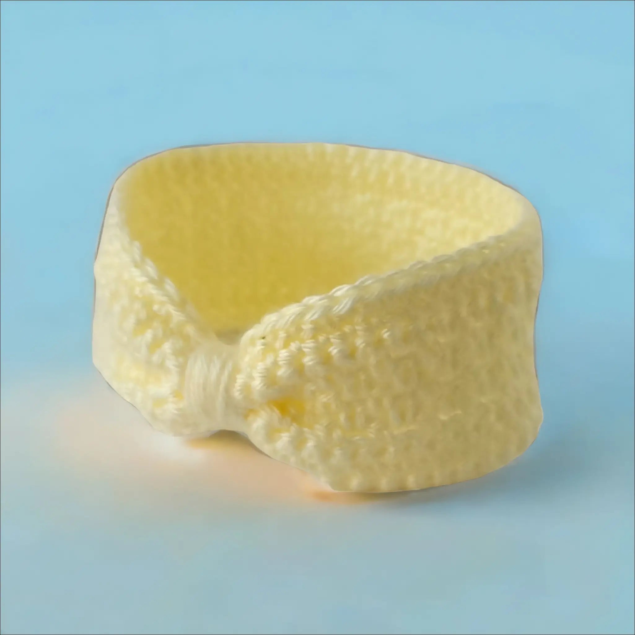Curved slice of pale yellow cheese beside Cozy Cream Ear-warmer Headband for 6-12 months