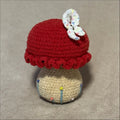 Crocheted mushroom with a red cap and decorative band on a beige background