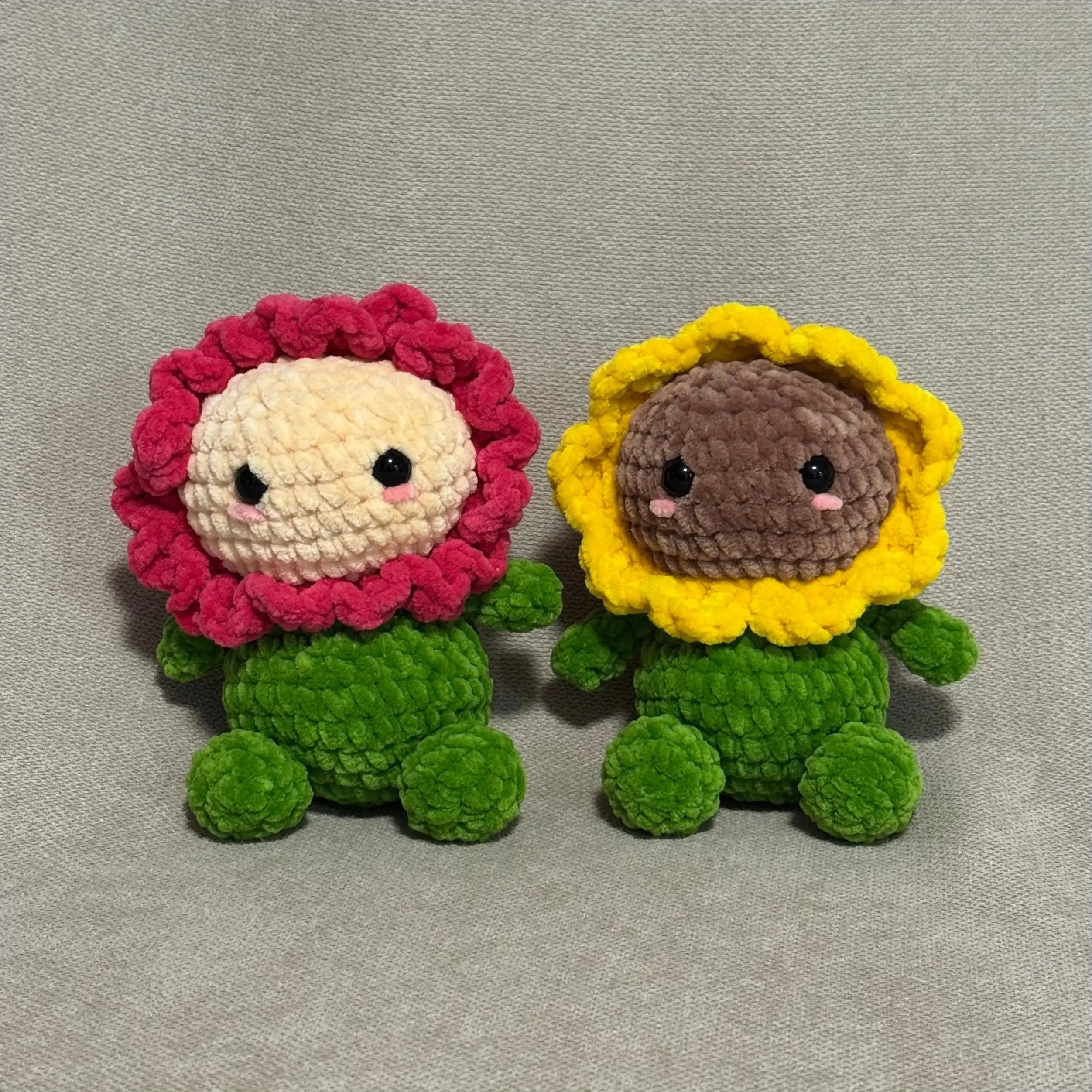 Two crochet flower characters with pink and yellow petals on a gray background