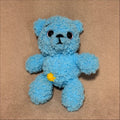 Blue teddy bear toy on a brown fabric background