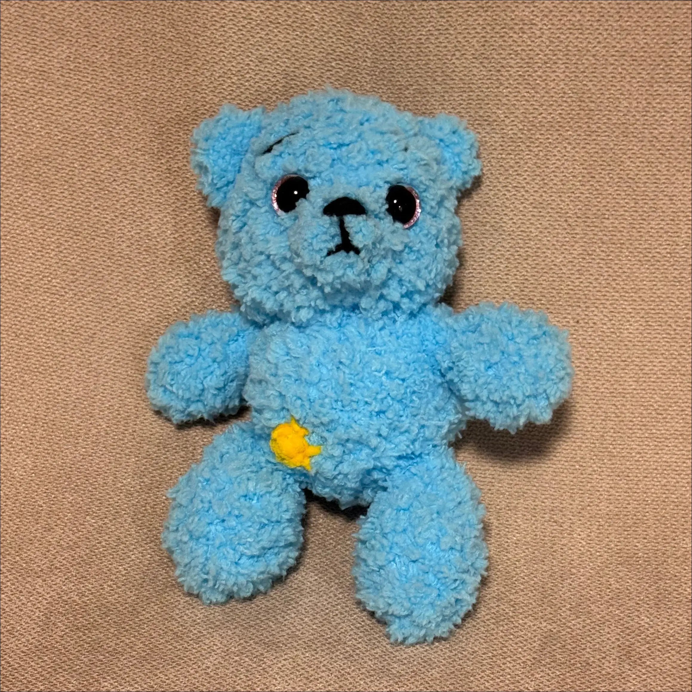 Blue teddy bear toy on a brown fabric background