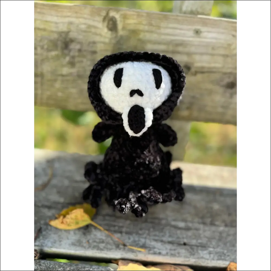 Crocheted black figure with a white face ghost face, perfect for Halloween decor