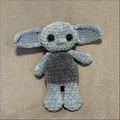 Gray crochet toy goblin on a beige surface