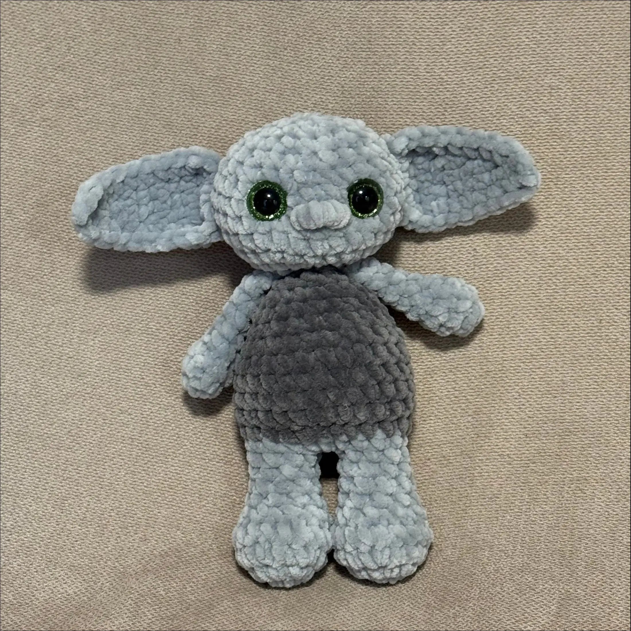 Gray crochet toy goblin on a beige surface