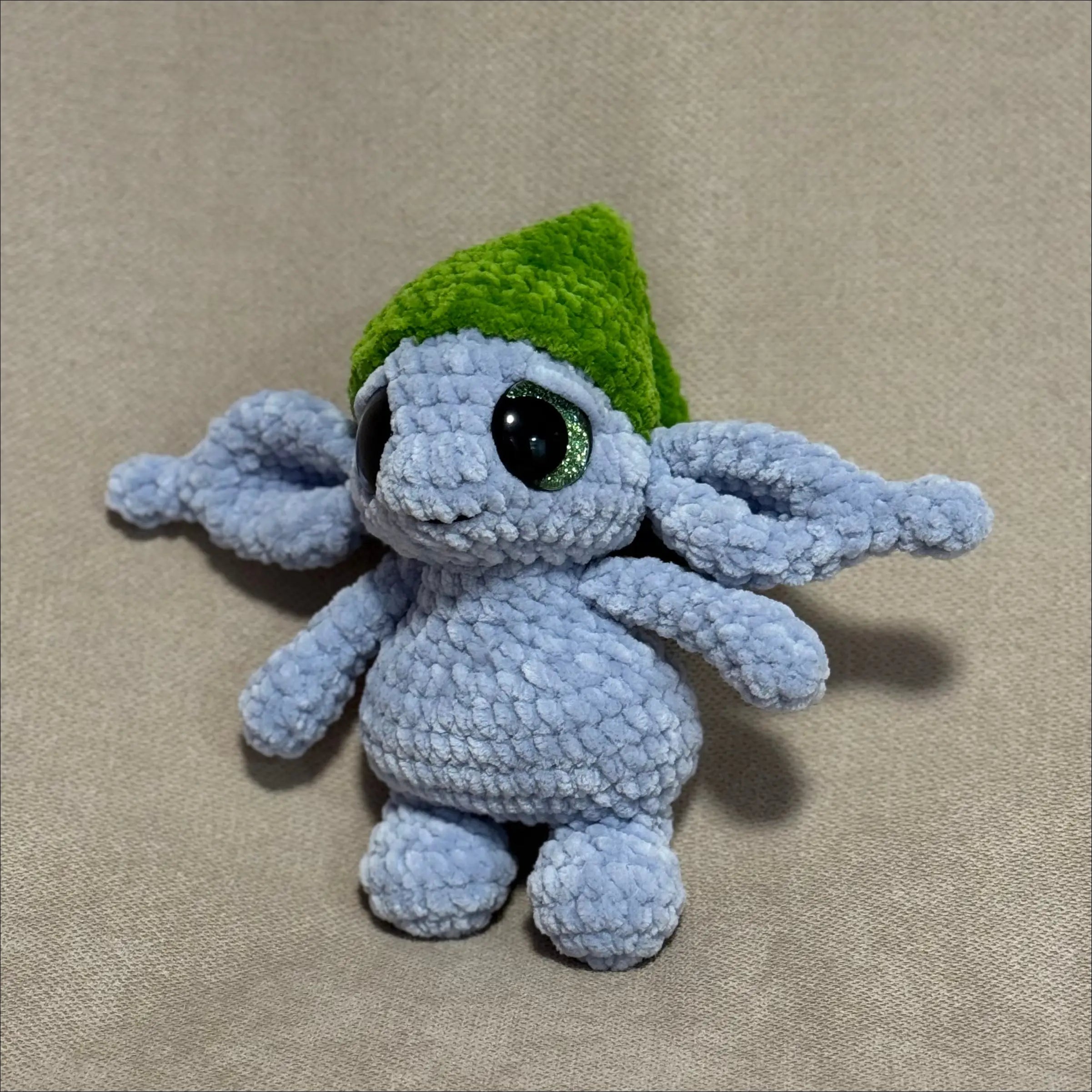 Crocheted goblin creature with a green hat on a beige background