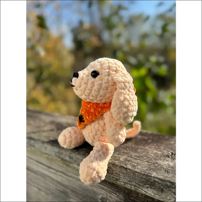 Crocheted bandana puppy toy with orange scarf on wooden surface ready for Halloween fun