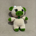 Crocheted cow toy with green accents on a beige background