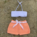 Crocheted baby bikini set featuring a white top and peachy shorts for summer fun