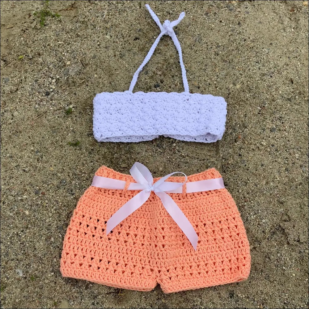 Crocheted baby bikini set featuring a white top and peachy shorts for summer fun