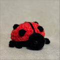 Crocheted ladybug toy on a beige fabric background
