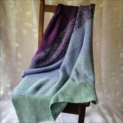 Cozy Luxe Gradient Baby Blanket in purple, blue, and green on a wooden chair