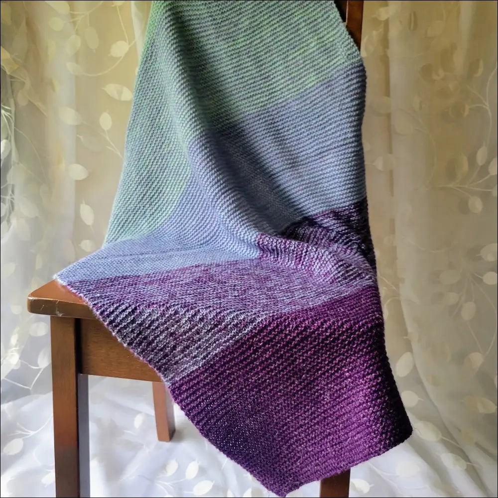 Luxe Gradient Baby Blanket in purple to blue-green draped over a cozy chair