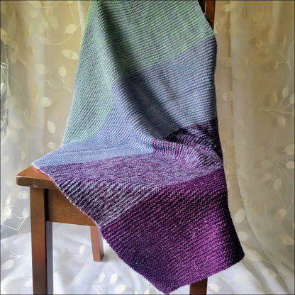 Luxe Gradient Baby Blanket in purple to blue-green draped over a cozy chair