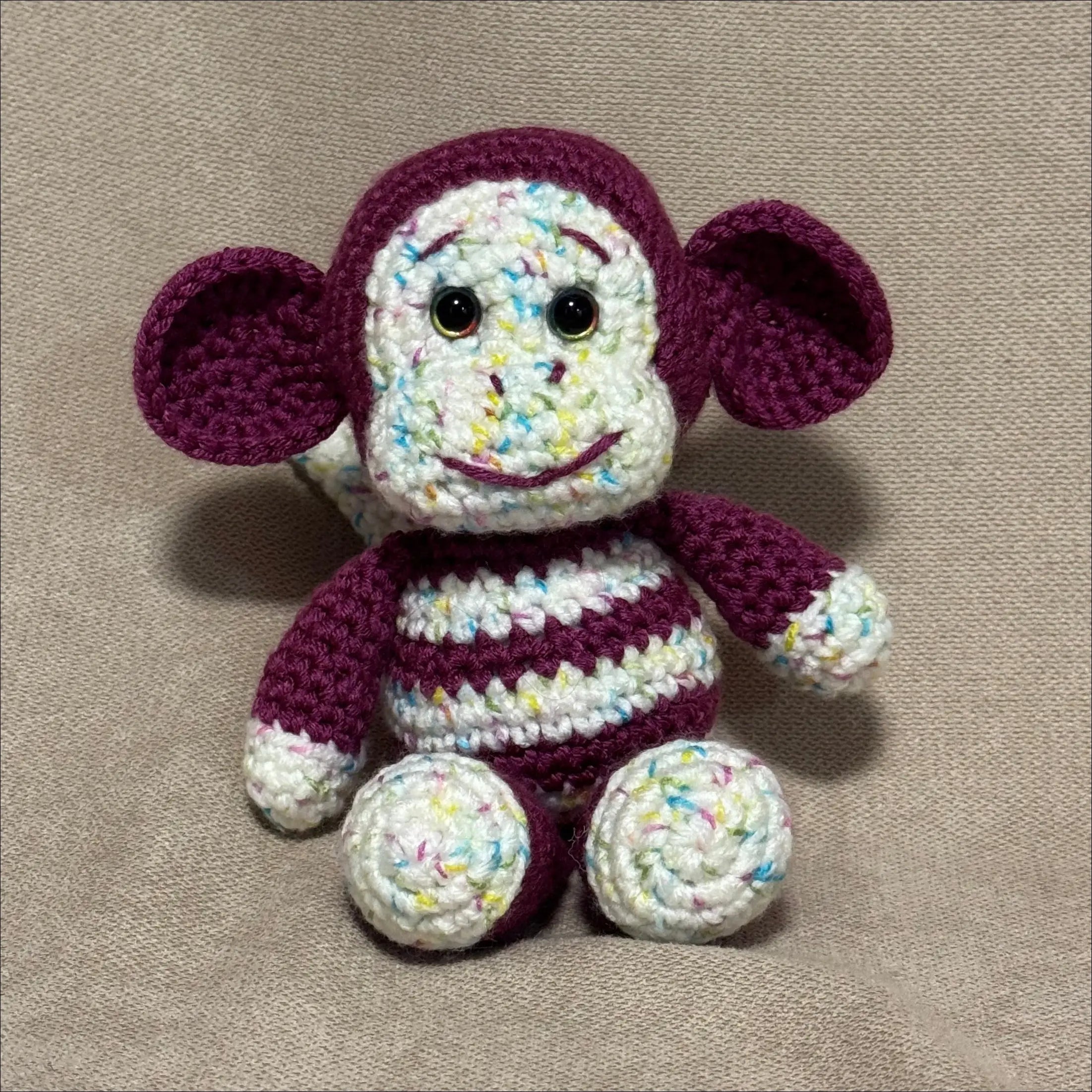 Crocheted monkey toy on a beige fabric background