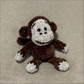 Crocheted monkey toy on a beige fabric background