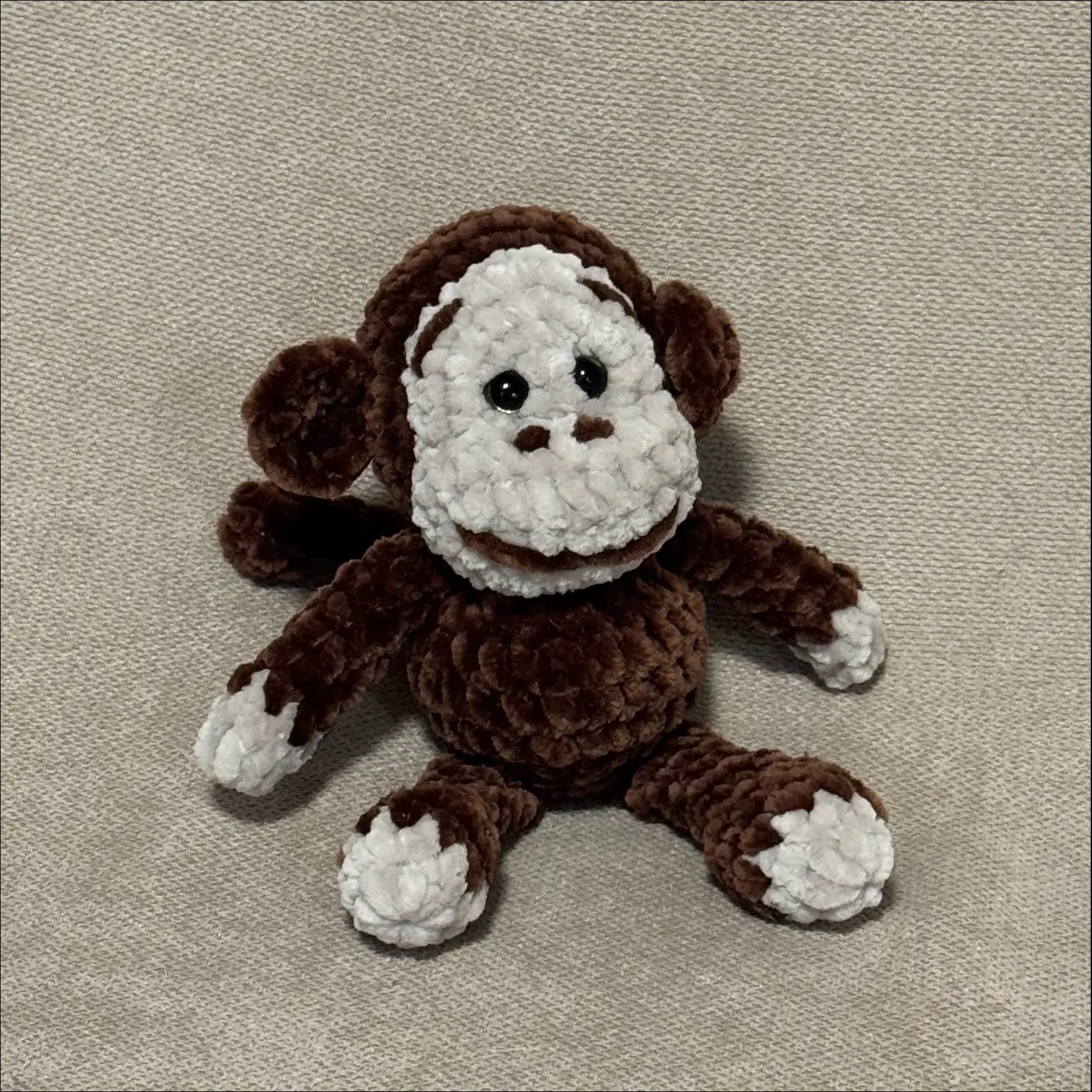 Crocheted monkey toy on a beige fabric background