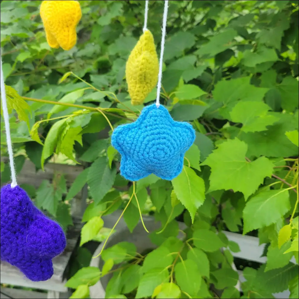 Bright blue crocheted star ornament in a Whimsical Moon & Stars Mobile among foliage