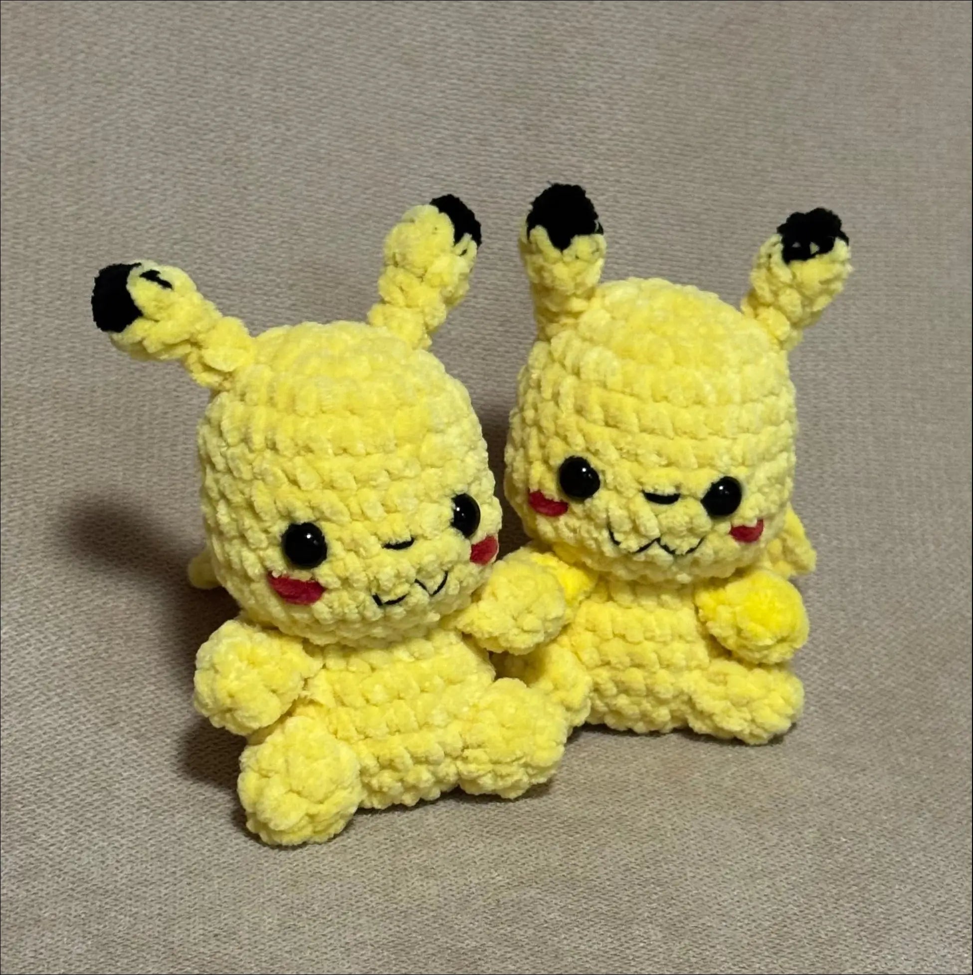 Two yellow plush toys with black ears on a gray background