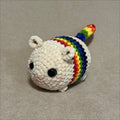 Crocheted unicorn plush toy with a rainbow mane on a beige background