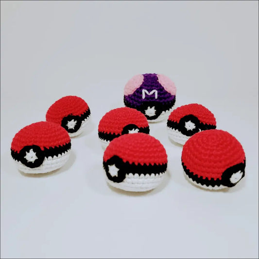 Colorful crocheted Pokeballs arranged on a white surface for catching all your favorite Pokémon