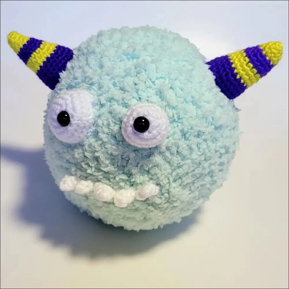 Fuzzy mint-green puff ball monster plush toy with striped horns and a big grin