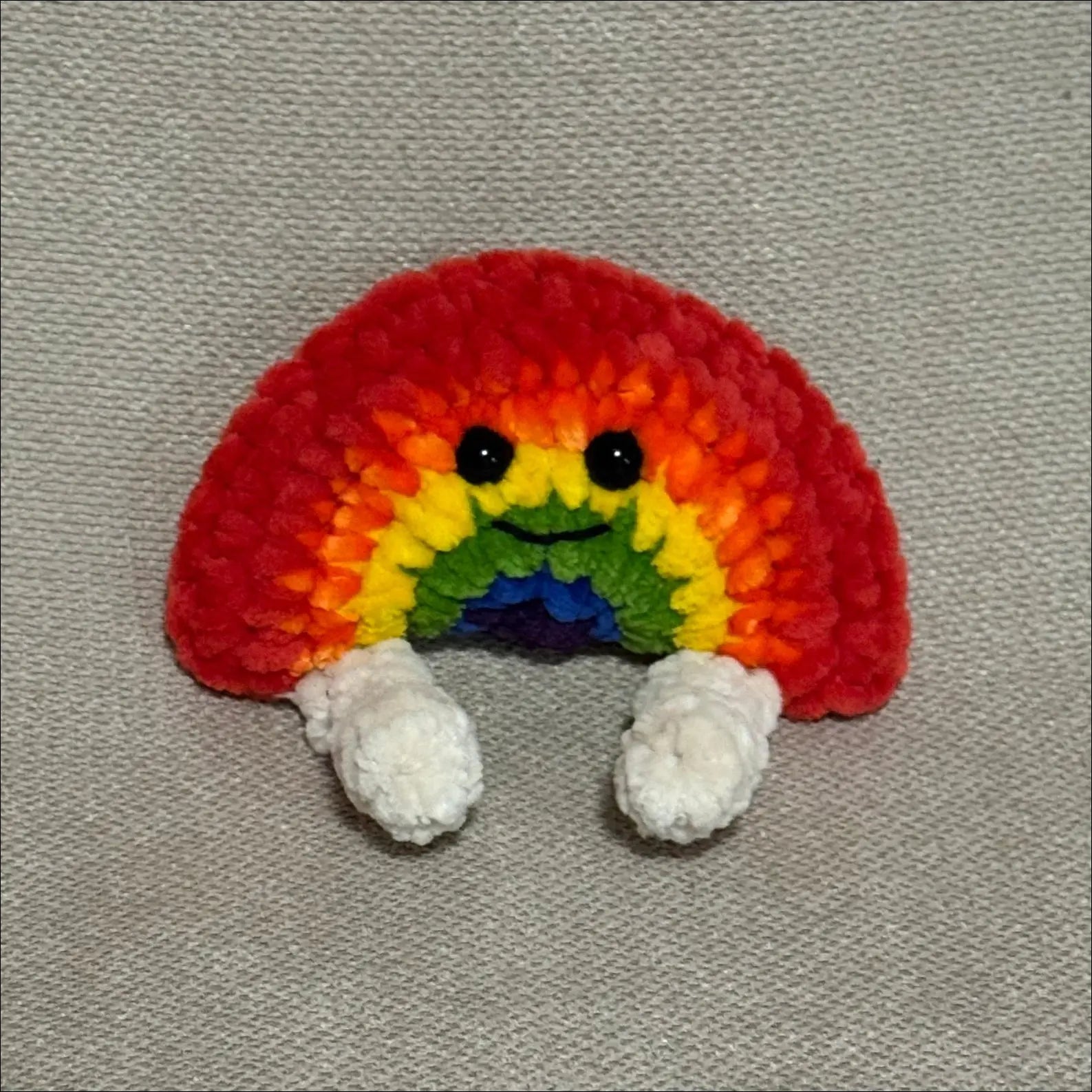 Colorful Rainbow with legs on a gray fabric backgound