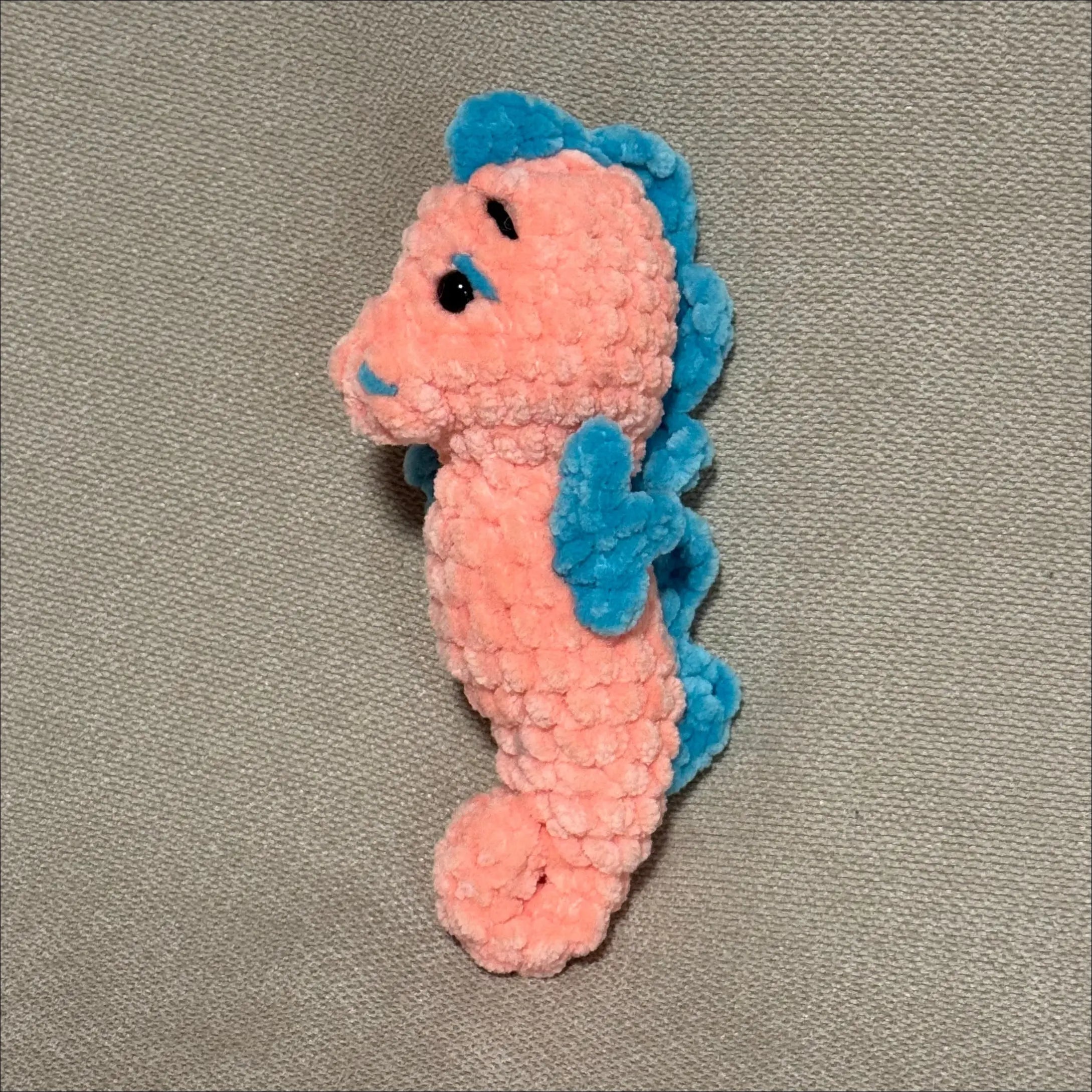 Crocheted seahorse toy on a gray background