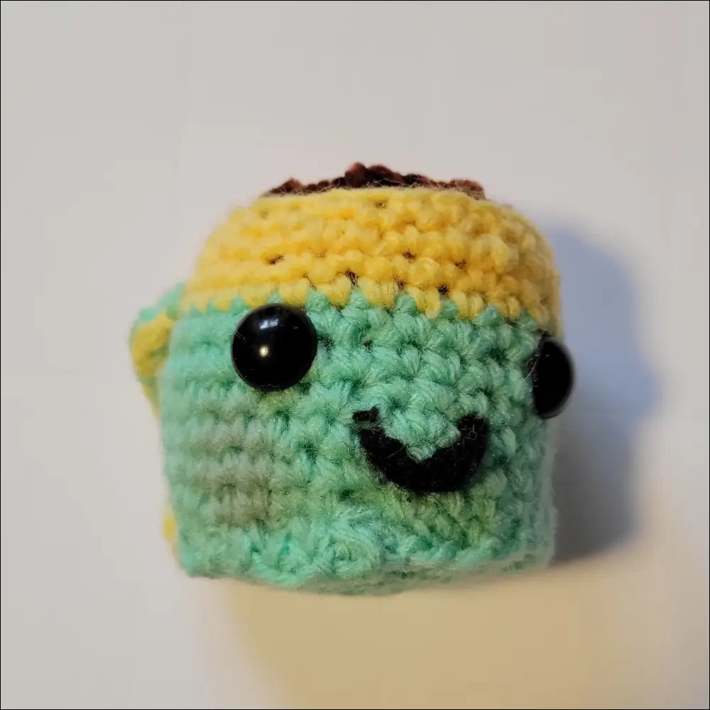 Small green and yellow crochet sea slug toy from Senior Makes, perfect for latte cup lovers