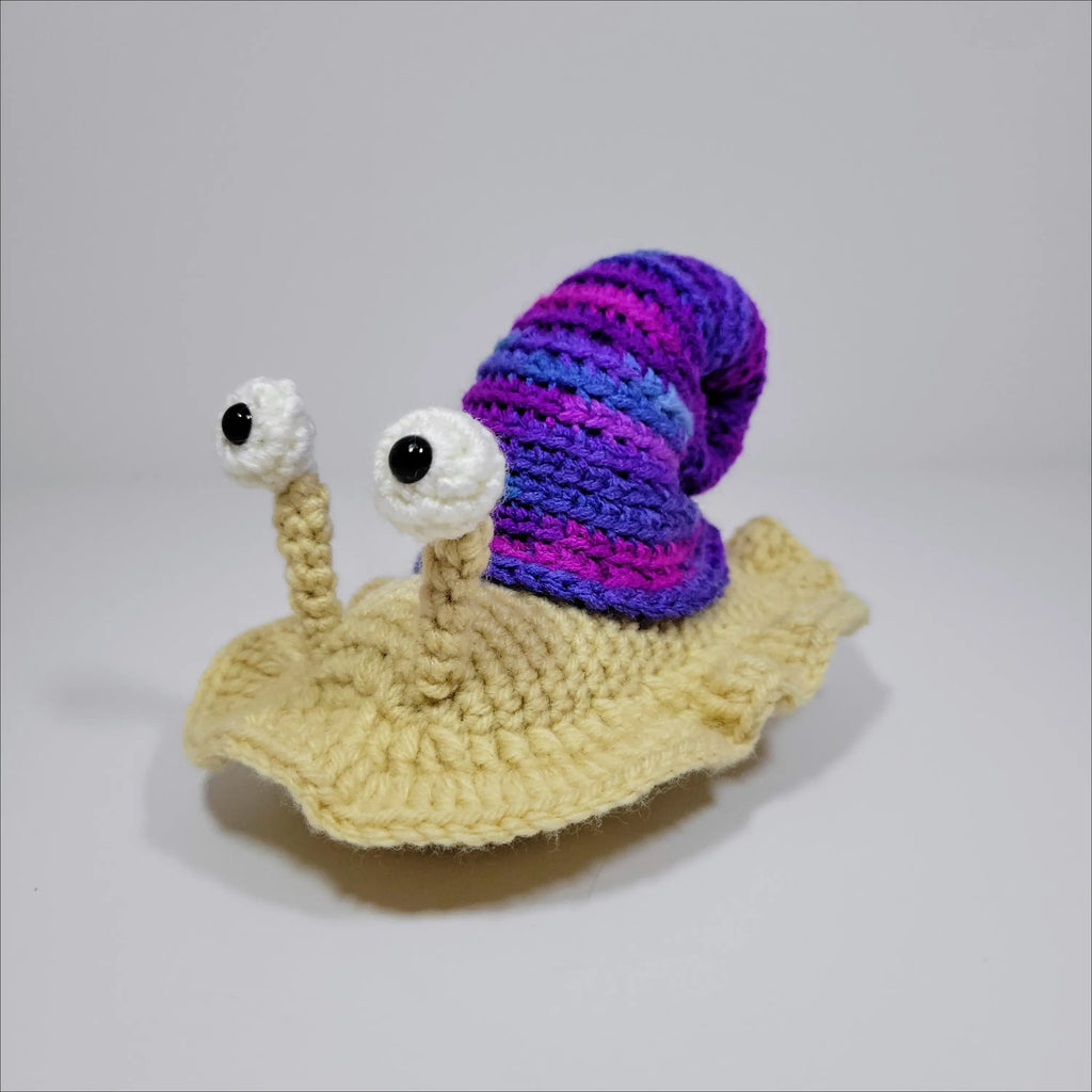 Cute hand-crocheted snail with a purple and blue shell in green yellow and grey pink
