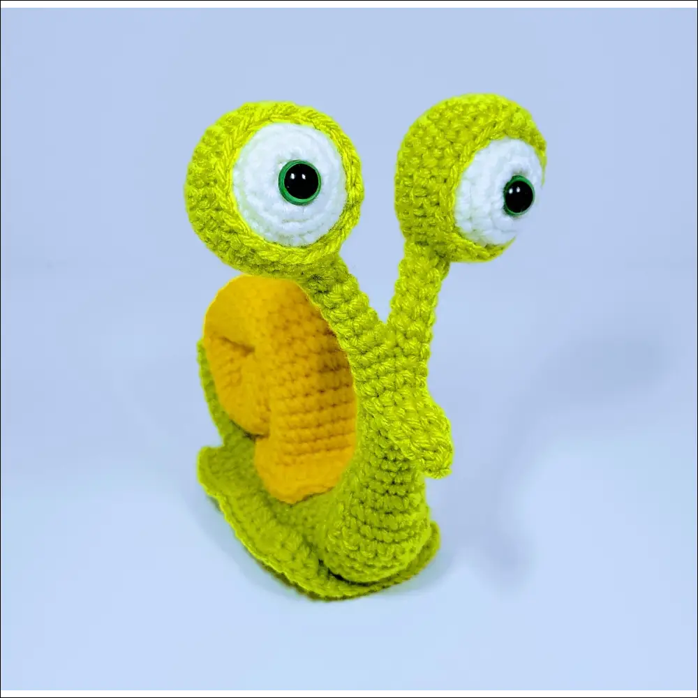 Adorable crochet snail toy with a green yellow face for cute decor in grey pink