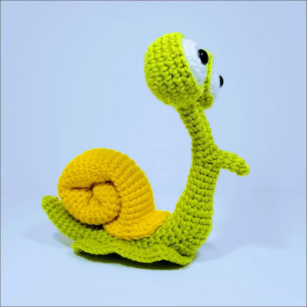 Cute hand-crocheted snail toy with a yellow shell in green yellow and grey pink colors