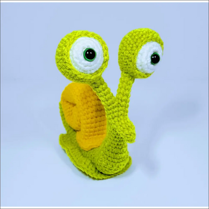 Adorable crochet snail toy with a green yellow face for cute decor in grey pink