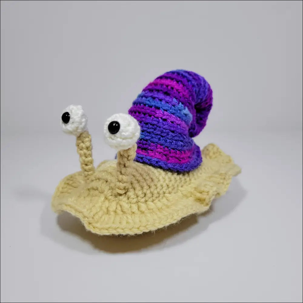 Cute hand-crocheted snail with a purple and blue shell in green yellow and grey pink