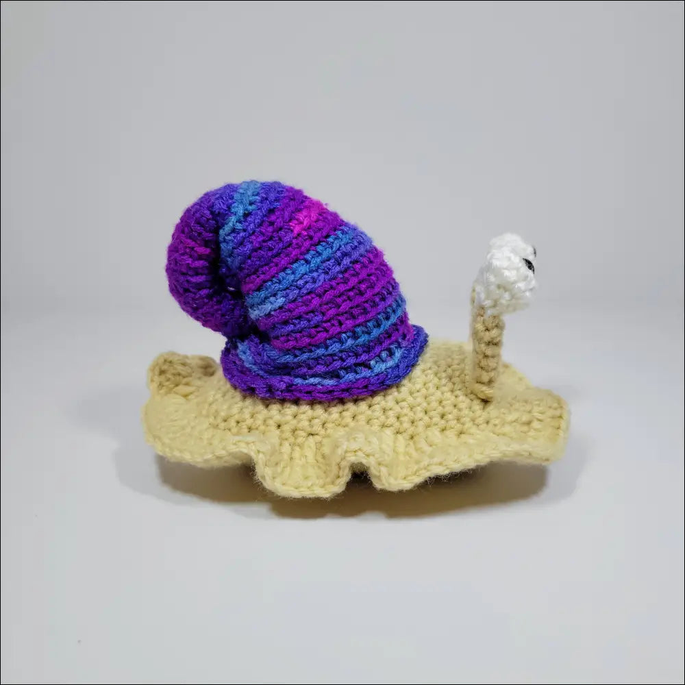 Cute Hand-crocheted Snail on white surface in green yellow and grey pink colors