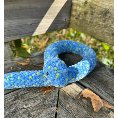 Blue and yellow plush snake coiled on wood, perfect for playtime with kids!