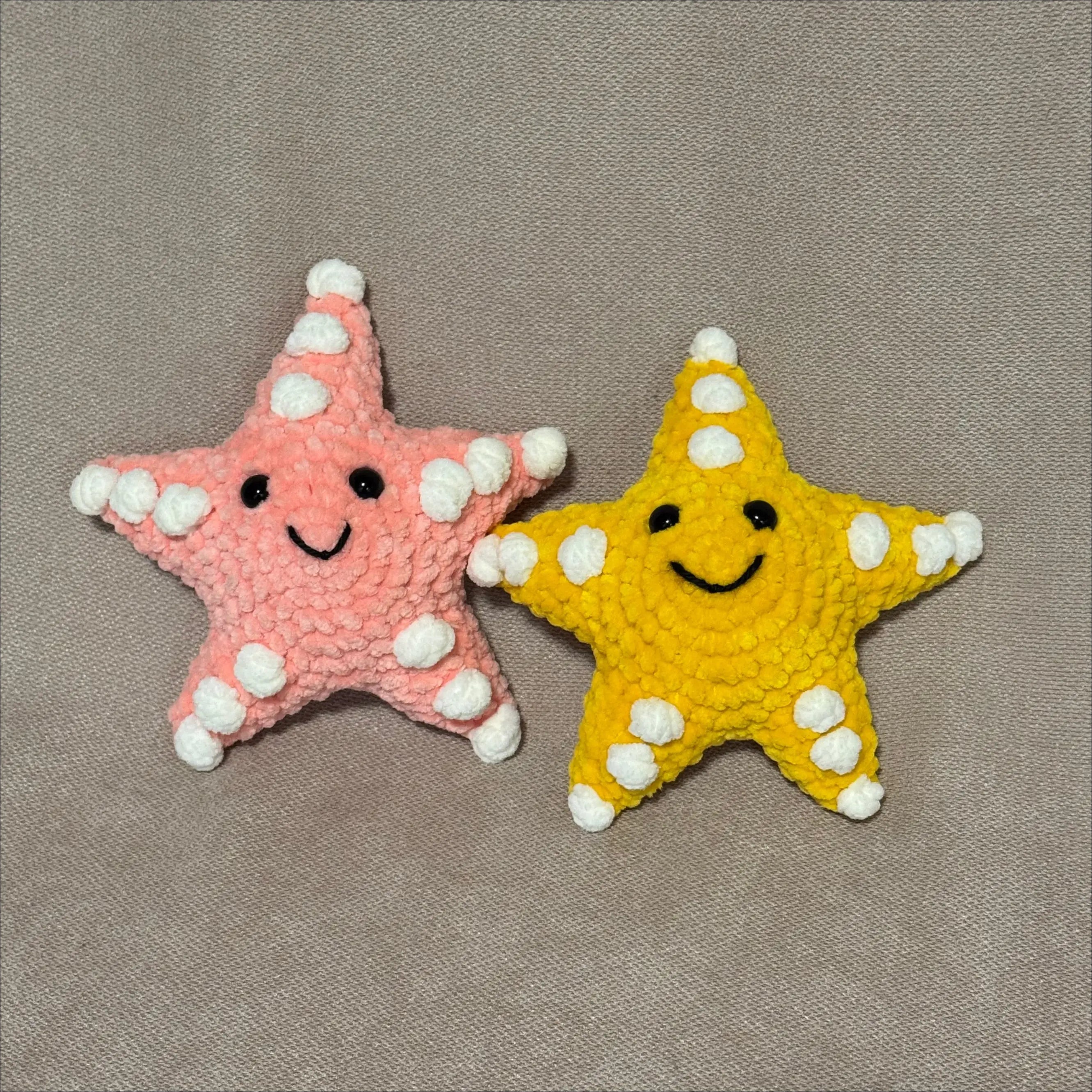 Two starfish toys, one yellow and one pink, on a gray background.