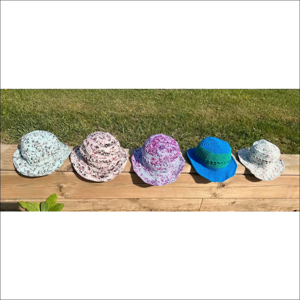 Five colorful Summer Fun Bucket Hats in cream, peach, and teal on a wooden surface