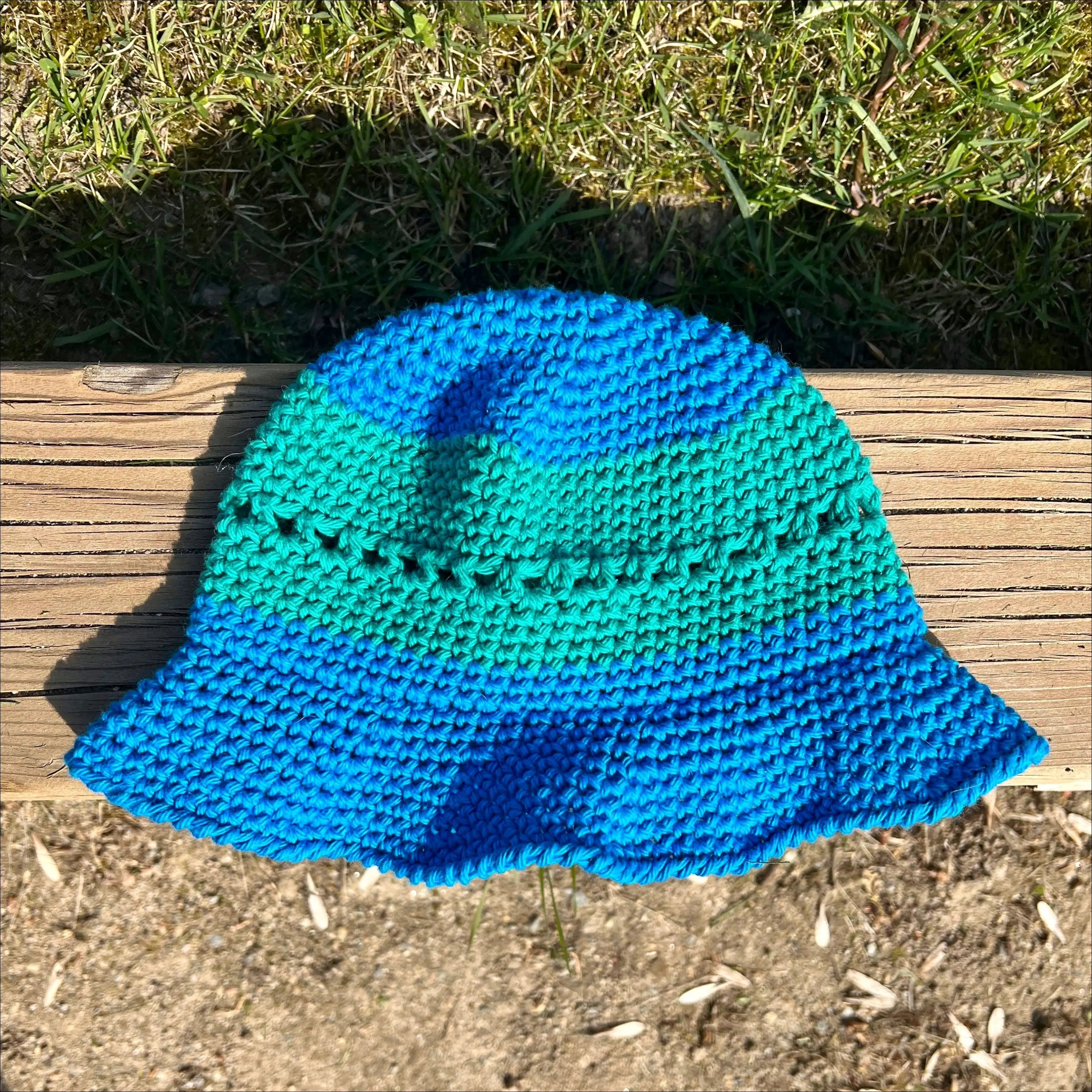 Crocheted blue and teal bucket hat for summer fun in cream, peach, and teal colors