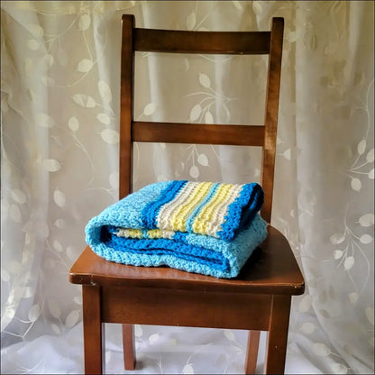 Wooden chair with a cozy textured baby blanket in blue and yellow stripes